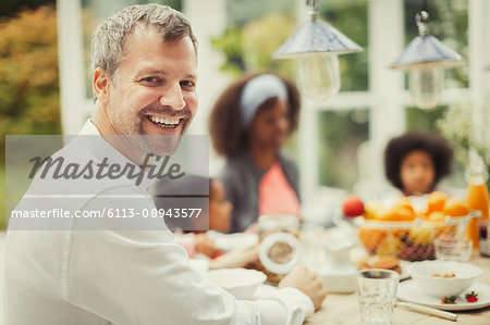 Portrait enthusiastic father with family at breakfast table