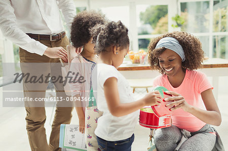 Mother preparing daughter's lunch box in kitchen