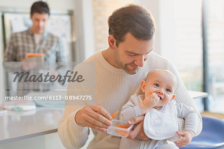 Father feeding carrots to baby son