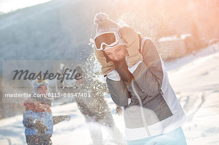 Playful skier friends enjoying snowball fight in snowy field