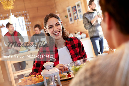Woman smiling at friend, eating at cabin table