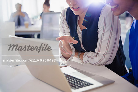 Businesswomen talking, working at laptop in office meeting
