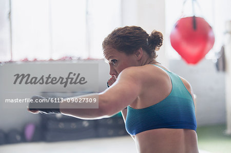 Determined female boxer shadowboxing in gym