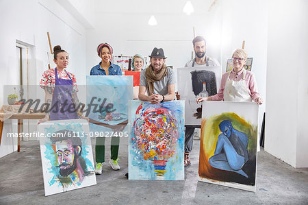 Portrait confident artists showing paintings in art class studio Portrait confident artists showing paintings in art class studio