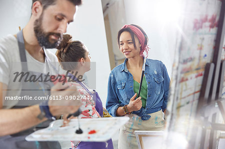 Artists talking and painting in art class studio