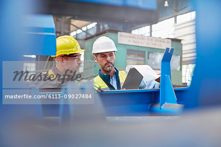 Male foreman and worker reviewing paperwork in factory