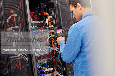 Male IT technician performing diagnostics on panel in server room