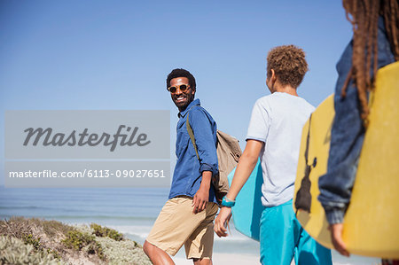 Portrait smiling father and children with boogie boards walking on sunny summer beach