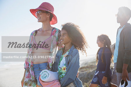 Smiling mother and daughter looking away on sunny summer beach