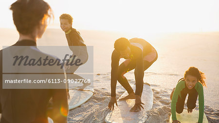 Father surfer teaching children surfing on surfboards on sunny summer beach