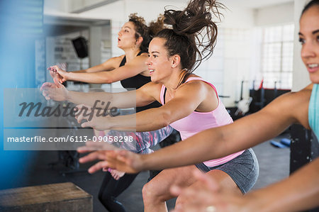 Energetic young women riding elliptical bikes in exercise class