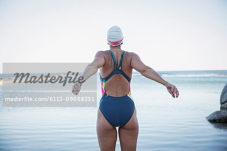 Female open water swimmer stretching at ocean