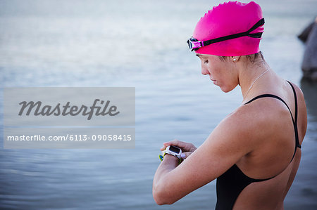 Female open water swimmer checking smart watch at ocean