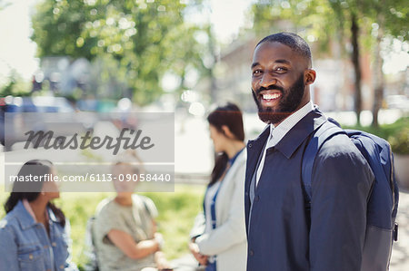 Portrait smiling businessman with backpack in urban park