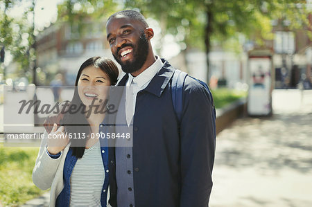 Smiling, affectionate young couple hugging in sunny urban park