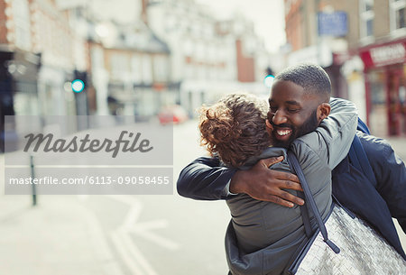 Happy, affectionate young couple hugging on sunny urban street