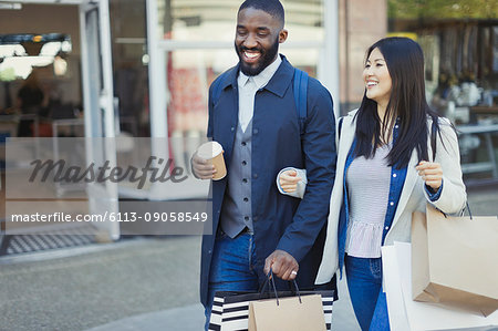 Smiling Young Couple Walking Arm In Arm Along Storefront With Coffee And Shopping Bags Stock Photo Masterfile Premium Royalty Free Code 6113