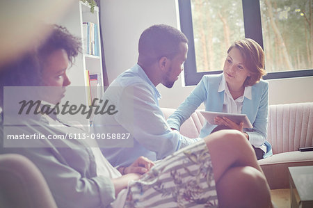 Female therapist with digital tablet comforting man in couples therapy session