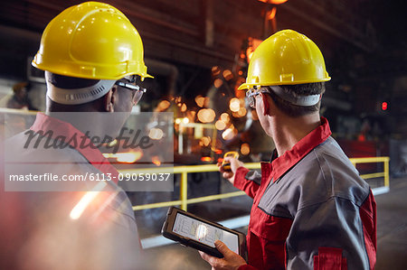 Supervisor and steel worker with digital tablet working in steel mill