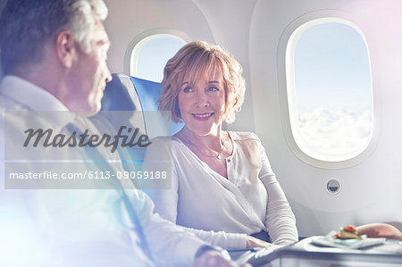 Businessman and businesswoman talking in first class on airplane Businessman and businesswoman talking in first class on airplane