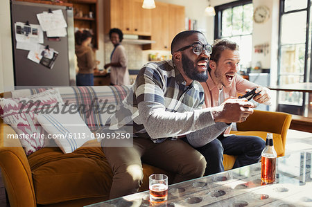 Male friends drinking beer and playing video game in living room
