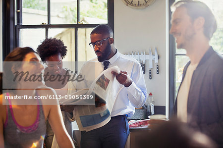 Friend roommates talking and reading newspaper in morning kitchen