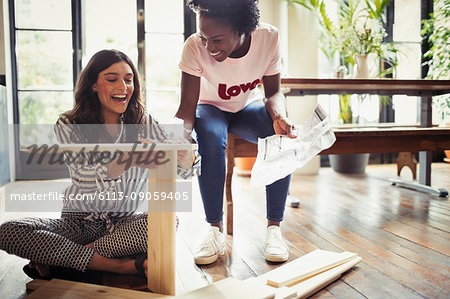 Women with instructions assembling furniture