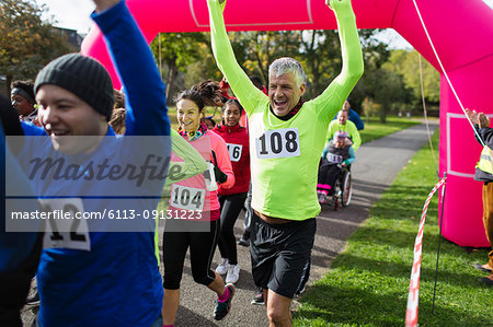 Enthusiastic runners cheering, crossing charity run finish line