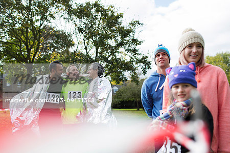 Male marathon runners wrapped in thermal blanket in park