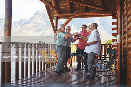 Active senior friends toasting wine glasses on cabin balcony