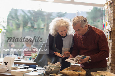 Senior couple looking at book in shop