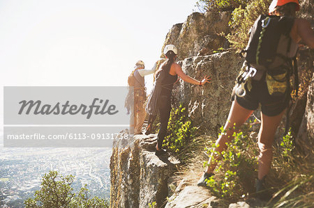 Rock climbers climbing rocks above sunny ocean