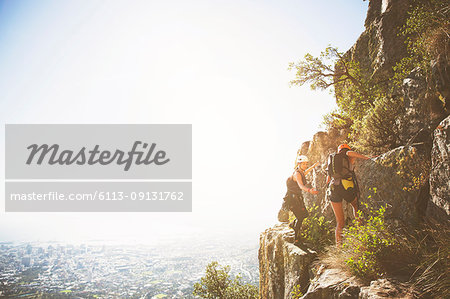 Rock climbers on sunny rocks above ocean