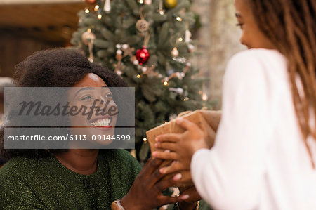 Smiling mother giving Christmas gift to daughter