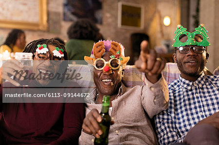 Portrait playful grandfather and grandsons wearing Christmas costume goggles