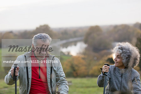 Active senior couple hiking with poles in park