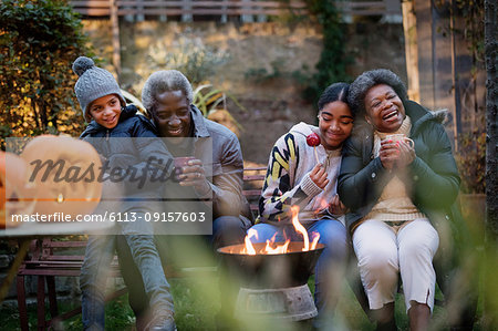 Grandparents and grandchildren enjoying autumn backyard campfire