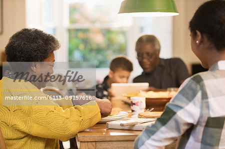 Family eating and using digital tablet at dining table
