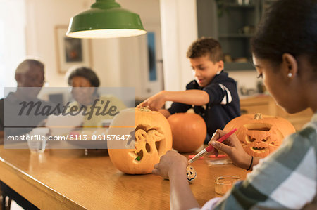 Grandparents at table with grandchildren carving Halloween pumpkins