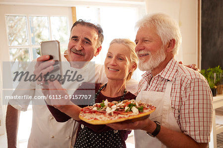 Chef and senior couple taking selfie with pizza in cooking class