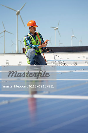 Engineer with equipment inspecting solar panels at sunny power plant