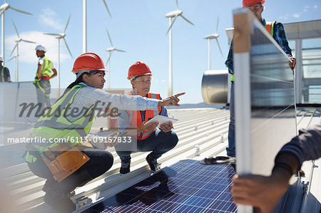 Female engineers talking, examining solar panels at power plant