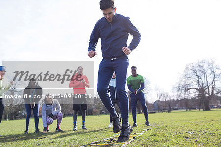 Focused man doing speed ladder drill in sunny park