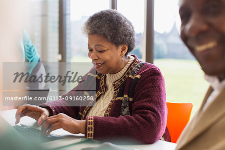 Smiling, confident senior businesswoman using laptop
