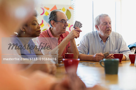 Senior friends playing cards at table in community center