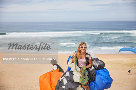 Portrait smiling, confident female paraglider with equipment on sunny ocean beach