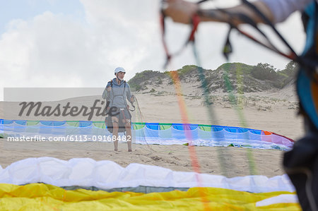 Male paraglider with parachute on beach