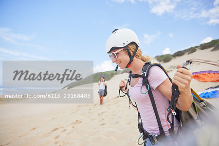 Smiling female paraglider with equipment on beach