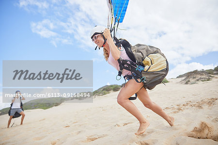 Female paraglider running, taking off on beach