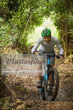 Happy man mountain biking on trail in woods